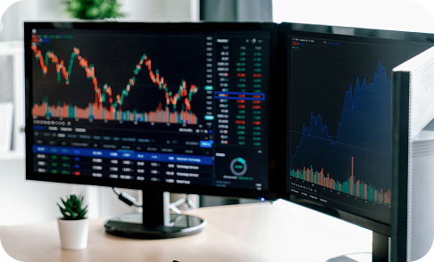 Dual monitors displaying stock market graphs and data.
