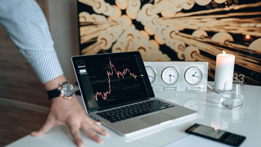 Desk setup with laptop displaying stock market charts and financial technology