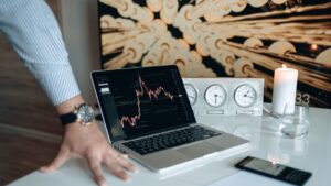 Desk setup with laptop displaying stock market charts and financial technology