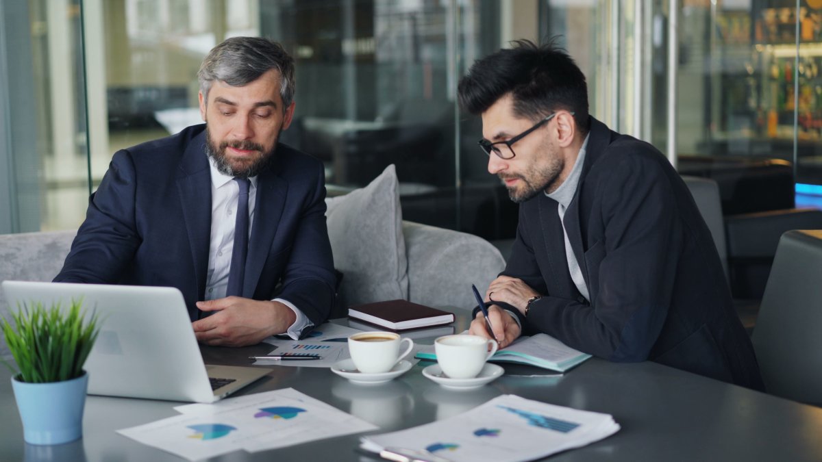 Two businessmen in suits reviewing charts and graphs in a modern office