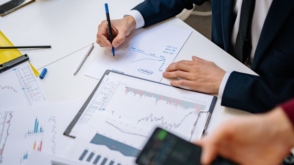 Hand writing on paper with financial charts, representing fee analysis and legal considerations