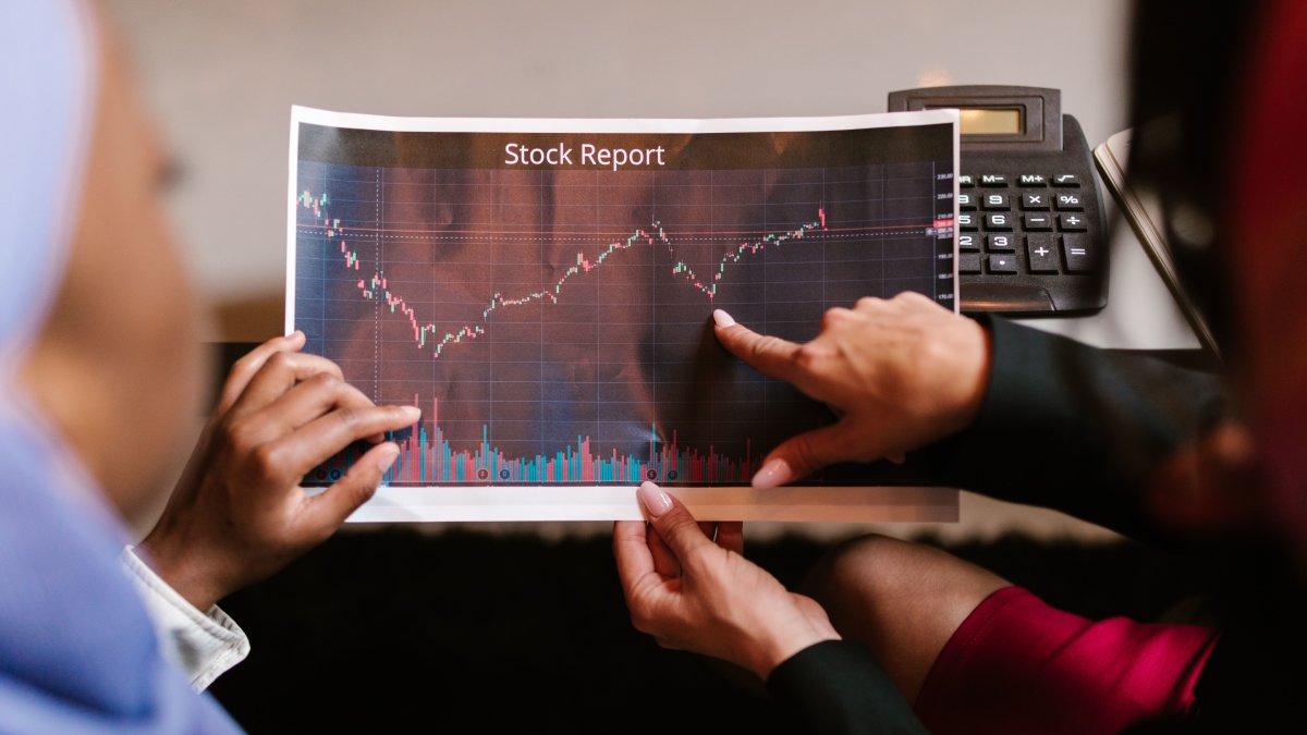 Two professionals discussing a stock report chart in a business meeting, symbolizing understanding risks and investment routes