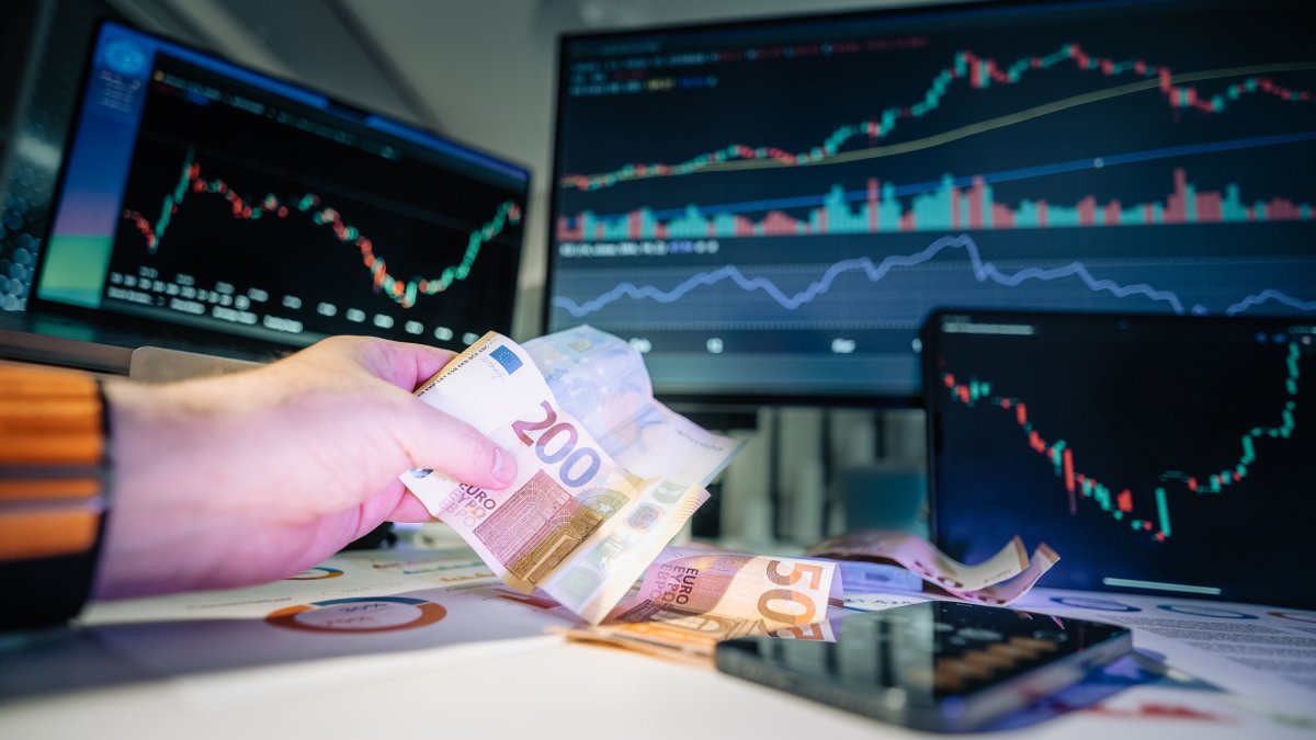 Close-up of euro banknotes with financial market graphs in the background